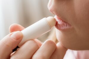 Young woman applies moisturizing balm to her lips